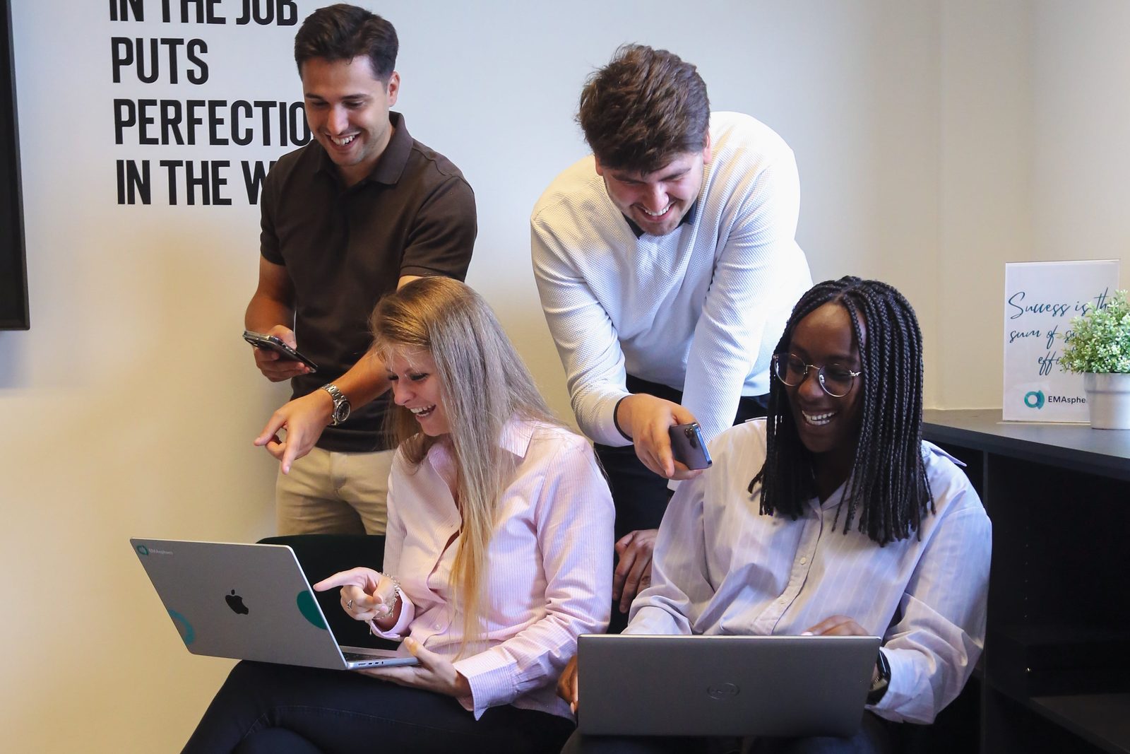 A smiling team gathered around laptops