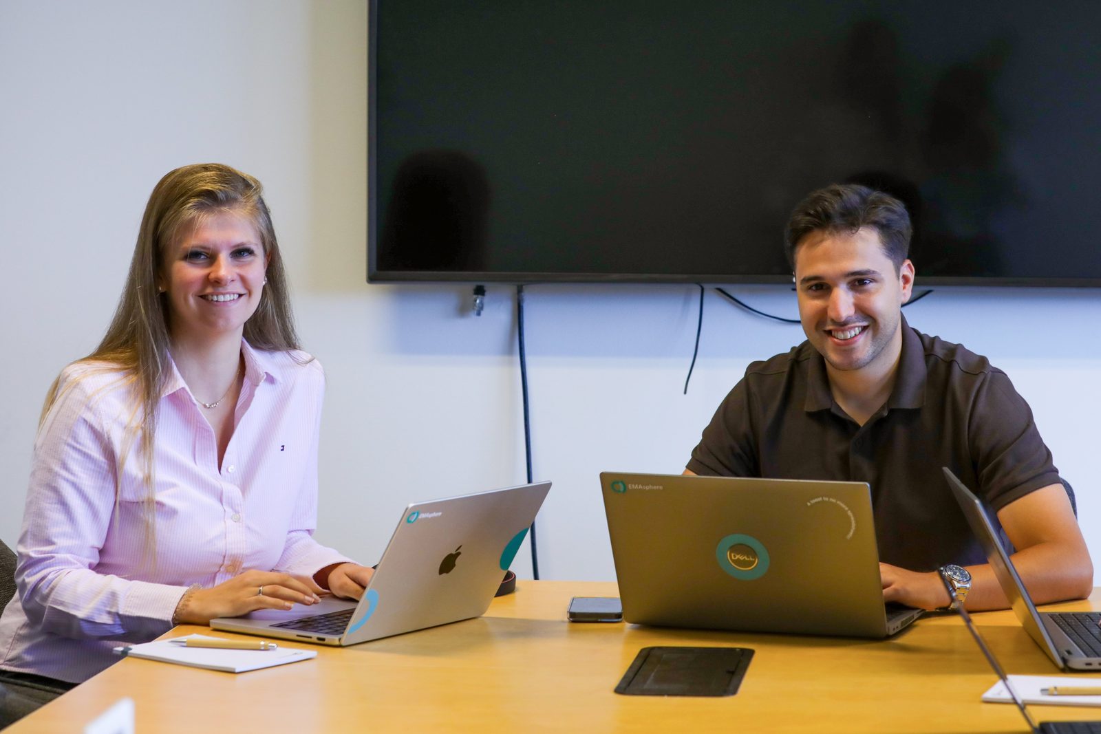 Two smiling colleagues in a meeting at their laptops